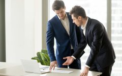 Businessman conducting presentation with business documents to convince investor to finance project. Realtor explaining benefits of estate object when showing drawings or construction plan to client