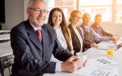 smiling-senior-manager-with-his-colleagues-sitting-together-in-the-meeting