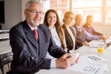 smiling-senior-manager-with-his-colleagues-sitting-together-in-the-meeting